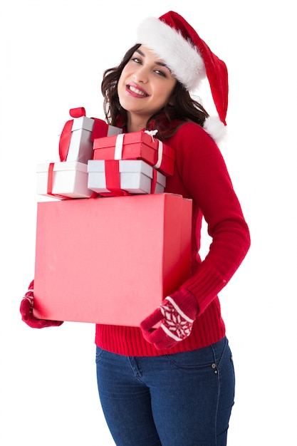 Happy brunette in santa hat holding many gifts 