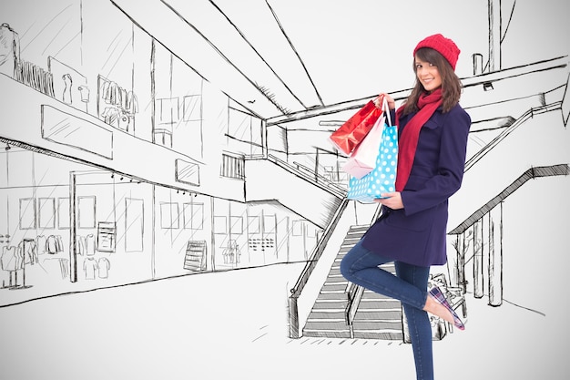 Happy brunette in winter clothes holding shopping bags against white background with vignette