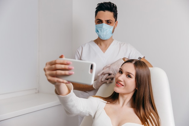 Happy brunette woman at beauty medical clinic. She is talking with doctor about face esthetics treatment.