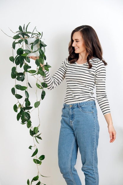 Happy brunette woman holding a potted plant in her hand looking at it