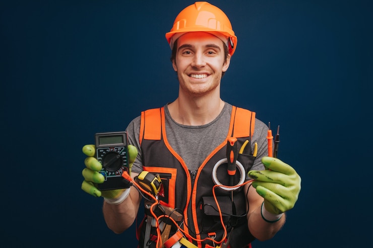 Photo happy builder is holding digital multimetert in gloves