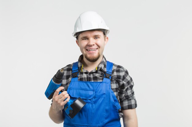 Happy builder standing with screwdriver on white wall