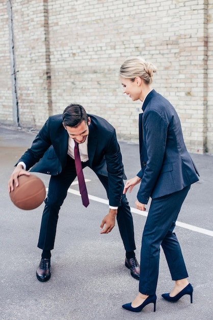 Happy business colleagues playing basketball outdoors