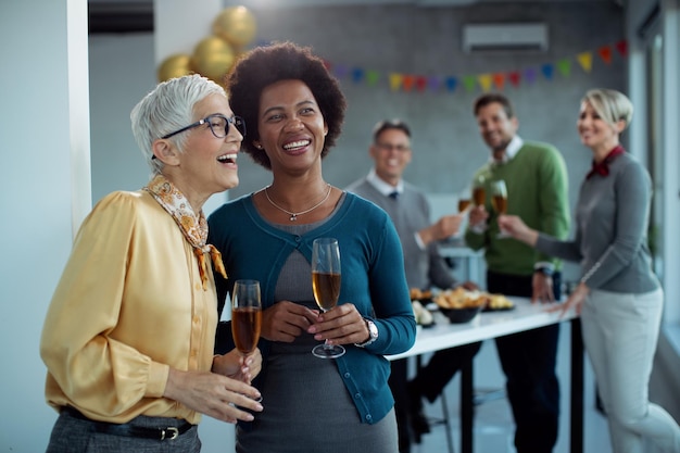 Felici i colleghi di lavoro che bevono champagne durante una festa in ufficio