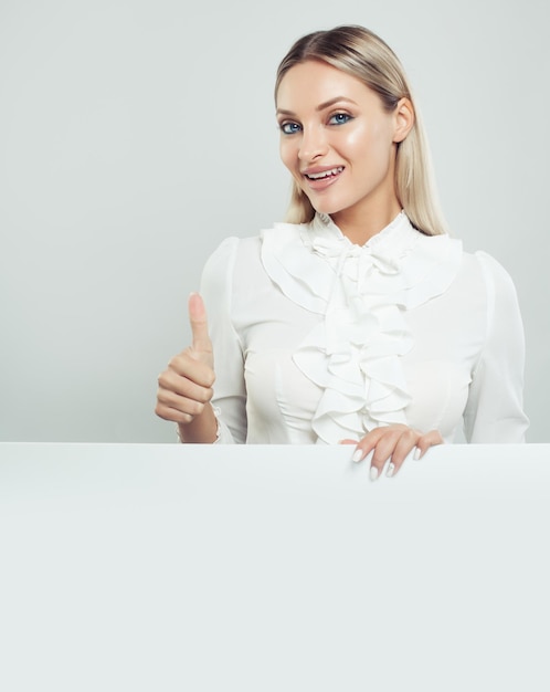 Happy business lady with thumb up and white empty board background with copy space for advertising marketing or product placement Successful business woman portrait
