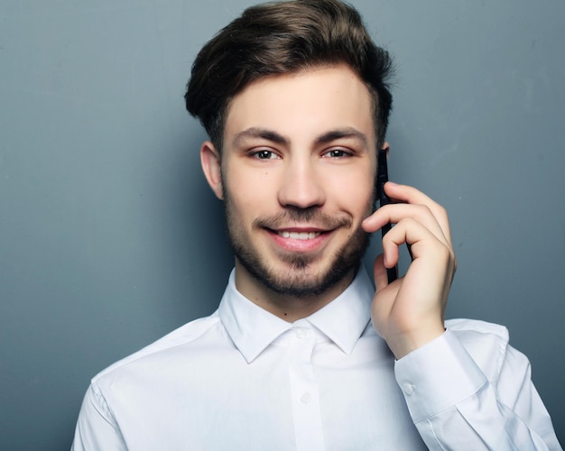 Happy business man calling with his smartphone against grey bac