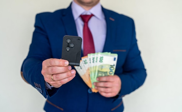 Happy business man holding car keys with euro money