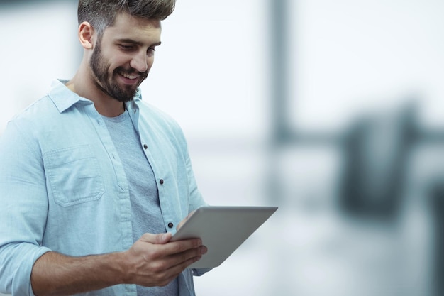 Happy business man using a tablet against blue blurred background