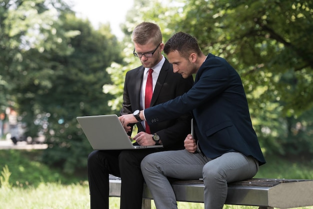 公園のベンチで外でタブレットPCを使用して幸せなビジネスの男性