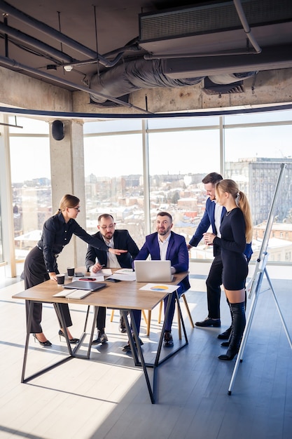 Happy business people looking at laptop presentation, success at work, sitting in modern office