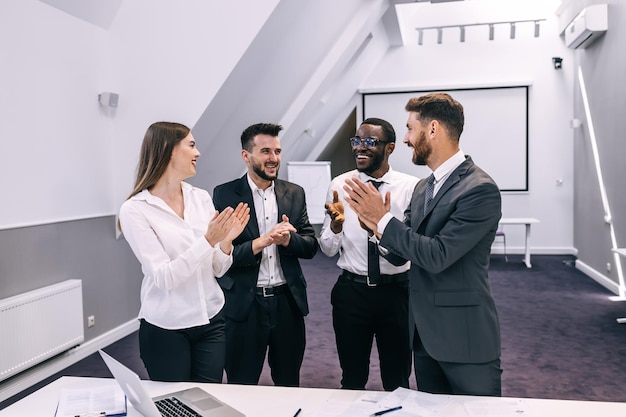 Happy business team clapping hands at workplace celebrating new