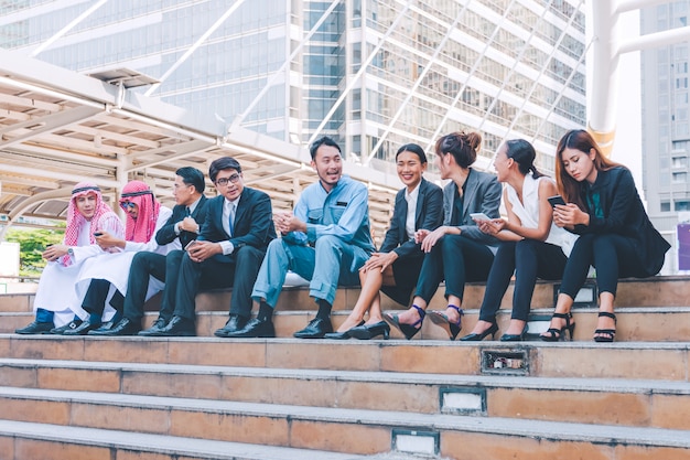 Happy business team making high hands in city background 