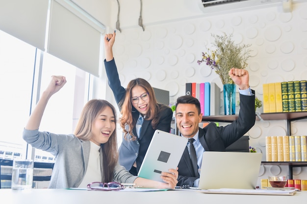 Happy business team with arm raised in office after meeting happy success