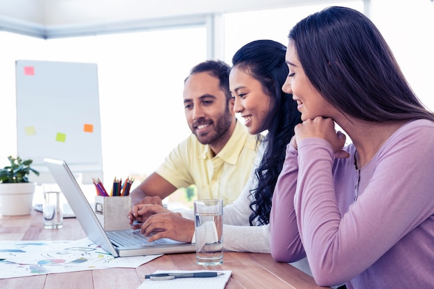 Happy business team working over laptop at conference room in creative office