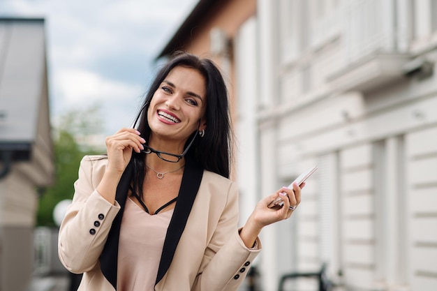 Happy business woman dressed in suit holding a cellphone ont
the hotel terrace