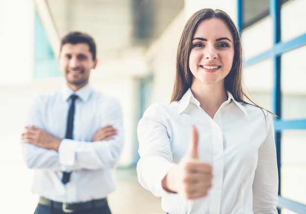 The happy business woman and man thumb up