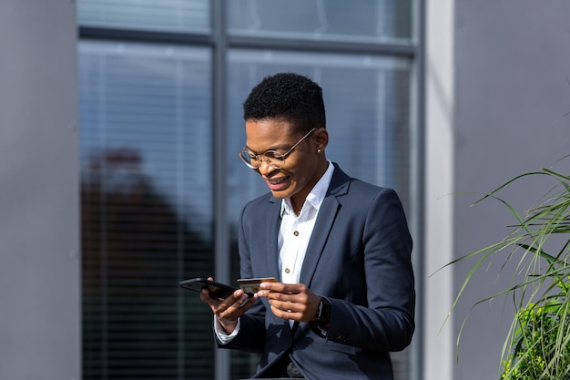 Happy business woman shopping online and transferring money using phone and credit card happy and smiling successful African American woman