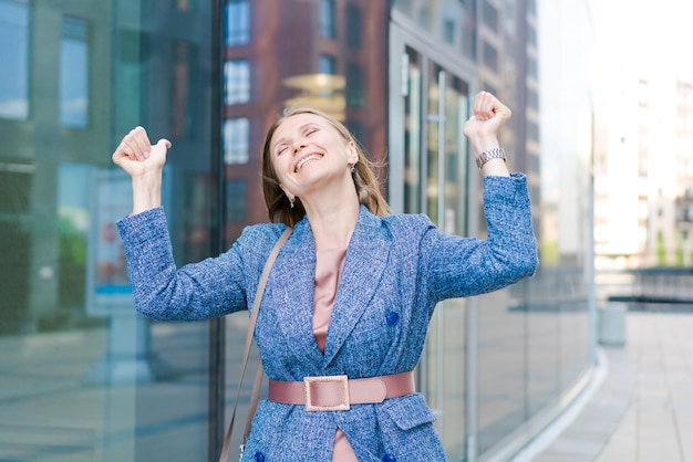 Photo happy business woman showing thumbs up while standing outdoors against office