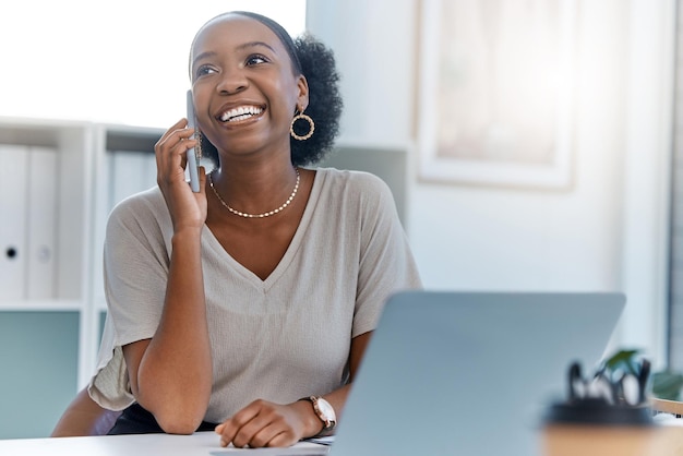 Happy business woman smile talking on phone call or young entrepreneur answering cellphone while sitting in front of work laptop in an office Female executive smiling and laughing at a funny joke