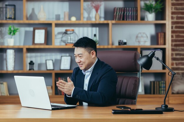 Счастливый бизнесмен празднует заключение успешного контракта, смотрит на экран ноутбука и радуется