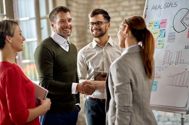 Happy businessman congratulating to female colleague on successful presentation during the meeting