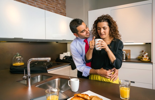 Happy businessman embracing to curly woman while having fast breakfast before go to work