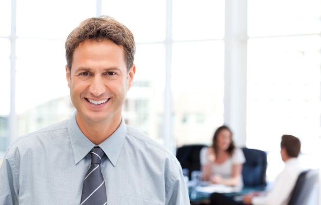 Happy businessman in the foreground while his team is working