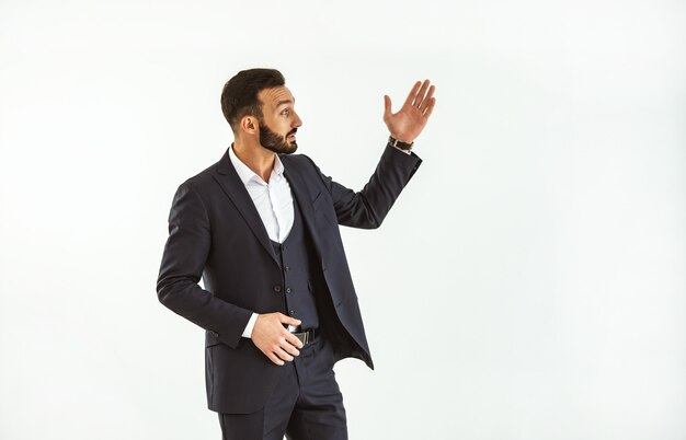 The happy businessman gesturing on the white wall background
