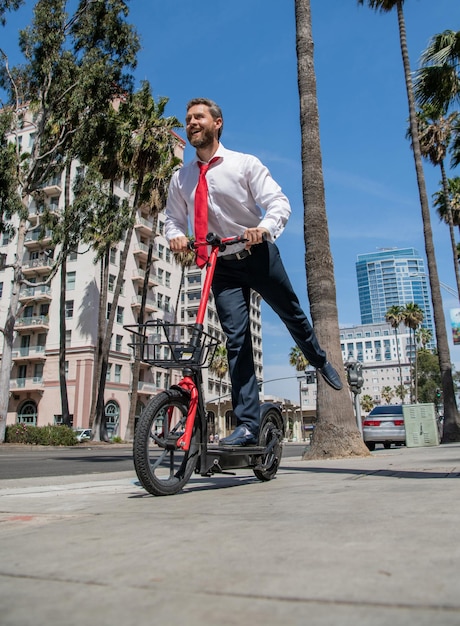 Happy businessman have fun riding escooter along city street escooting