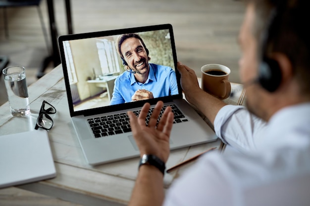 Photo happy businessman having a video call over laptop with his colleague while working in the office