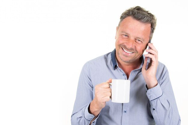 Happy businessman holding morning mug tea and speaking phone