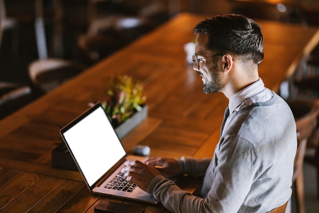 A happy businessman is working remotely from restaurant on a laptop