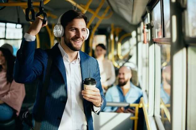 버스로 출퇴근하는 동안 헤드폰을 통해 음악을 듣는 행복한 사업가