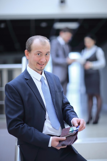 Happy businessman opens walletphoto on the background of office