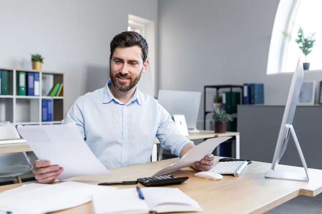 Happy businessman at paper work examining financial documents man at work working in the office