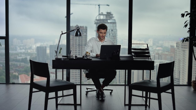 Happy businessman reading good news on laptop screen at office workplace