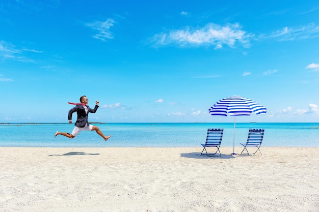 写真 熱帯のビーチでの仕事から走っている幸せなビジネスマン夏休みのコンセプト