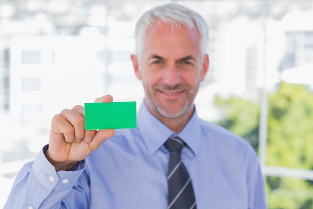 Happy businessman showing green business card