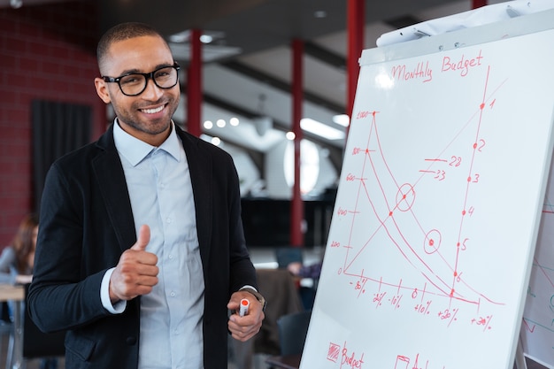 Photo happy businessman showing ok sign at the flipchart in the office