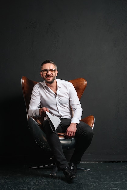 Happy businessman sitting isolated reading newspaper.