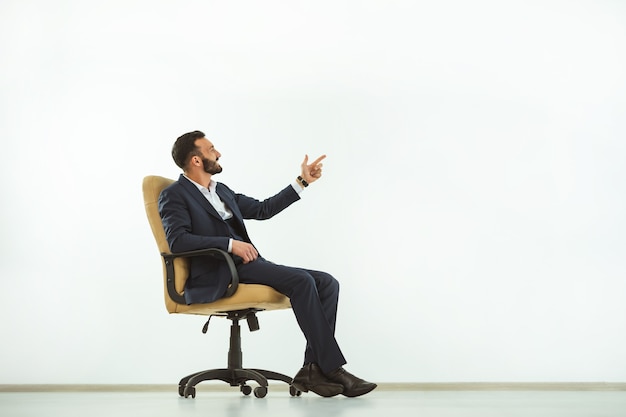 The happy businessman sitting on an office chair and gesturing