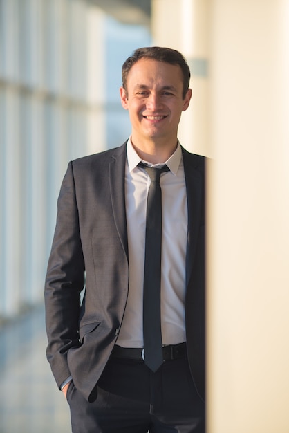 The happy businessman stand near the column