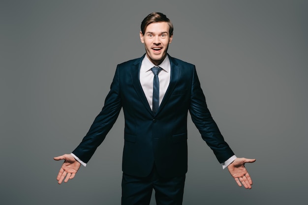 Happy businessman standing with opened arms isolated on grey