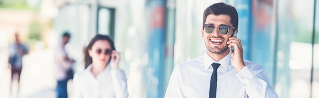 The happy businessman in sunglasses phone near the woman with a suitcase