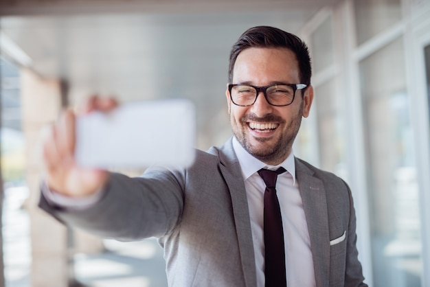 Happy businessman taking selfie outdoors. Selective focus on th face.