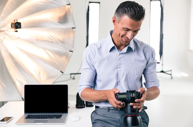 Uomo d'affari felice che utilizza la macchina fotografica in studio