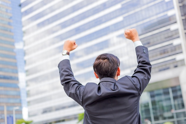 ¡happy businessman while standing outdoors with office building