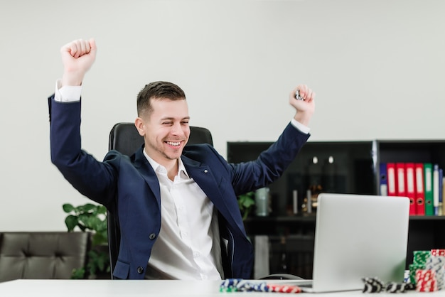 Happy businessman wins in online casino while playing poker in the office at workplace