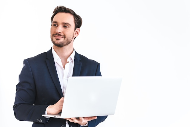 The happy businessman with a laptop standing on the white wall background