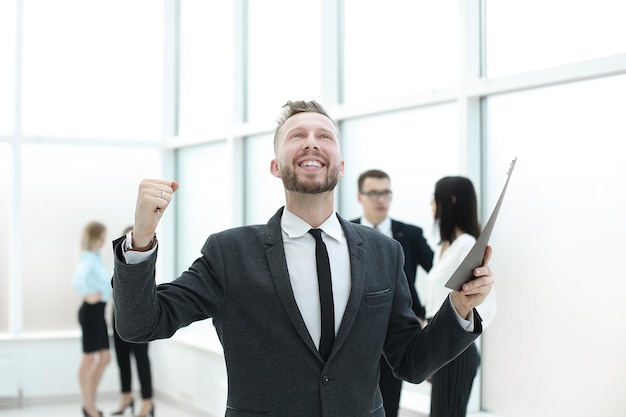 Happy businessman with the new contract standing in the lobby of the business center